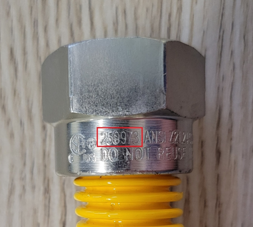 Close-up view of the flare nut on the recalled gas connector with CSA file number "259973" engraving