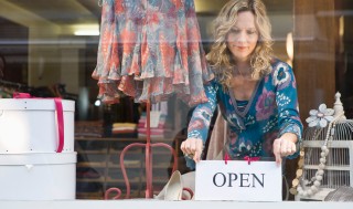 image of woman placing 'open' sign in store window